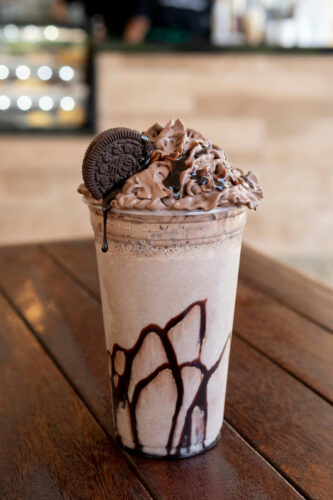 Chocolate protein powder smoothie topped with whipped cream and cookie.