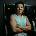 Best protein for men over 40: Confident, muscular man over 40 in athletic wear, arms crossed in a gym setting, symbolizing strength and vitality.