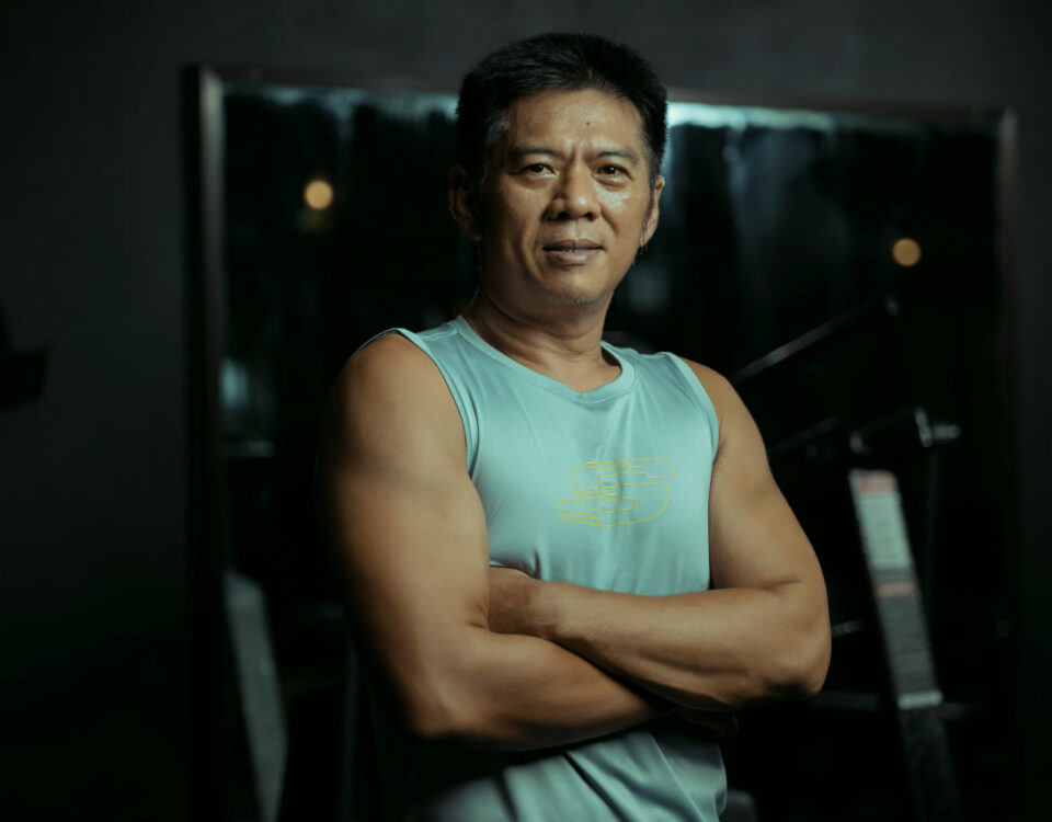 Best protein for men over 40: Confident, muscular man over 40 in athletic wear, arms crossed in a gym setting, symbolizing strength and vitality.