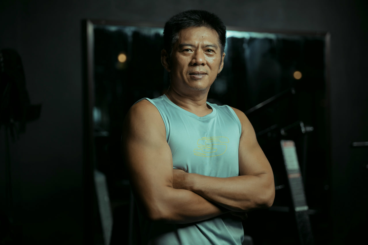 Best protein for men over 40: Confident, muscular man over 40 in athletic wear, arms crossed in a gym setting, symbolizing strength and vitality.