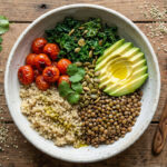 Protein in vegan diets: colorful Buddha bowl with quinoa, lentils, roasted tomatoes, kale, avocado, and seeds – a nutrient-dense whole-food meal